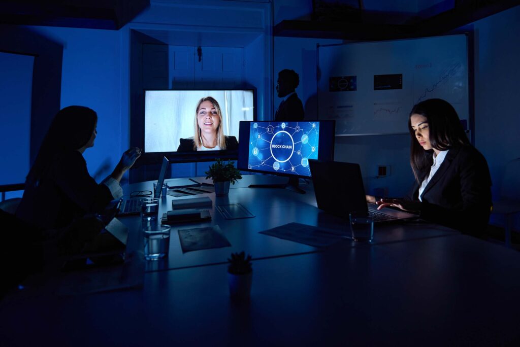 Unrecognizable attentive female coworkers with netbooks at table during video call on monitor in workspace