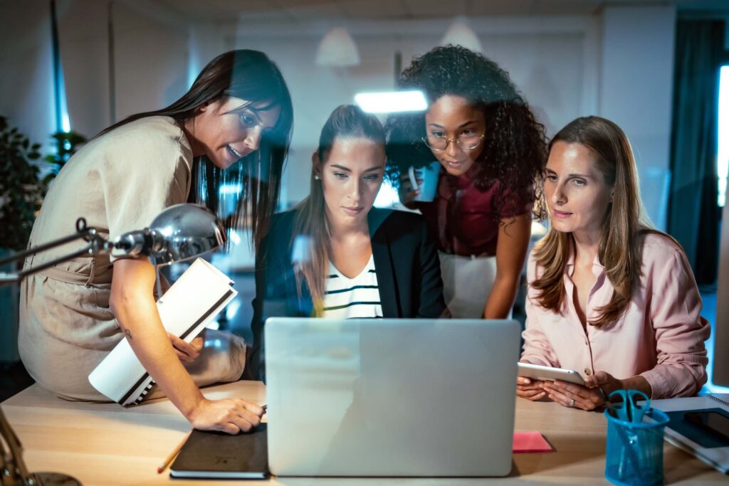 Shot of four smart businesswomen talking and reviewing the latest work done on the computer in a joint workspace.